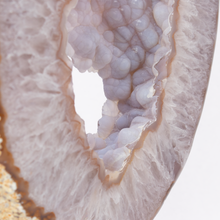 Load image into Gallery viewer, Close-up of a geode with crystal formation inside, on a light background