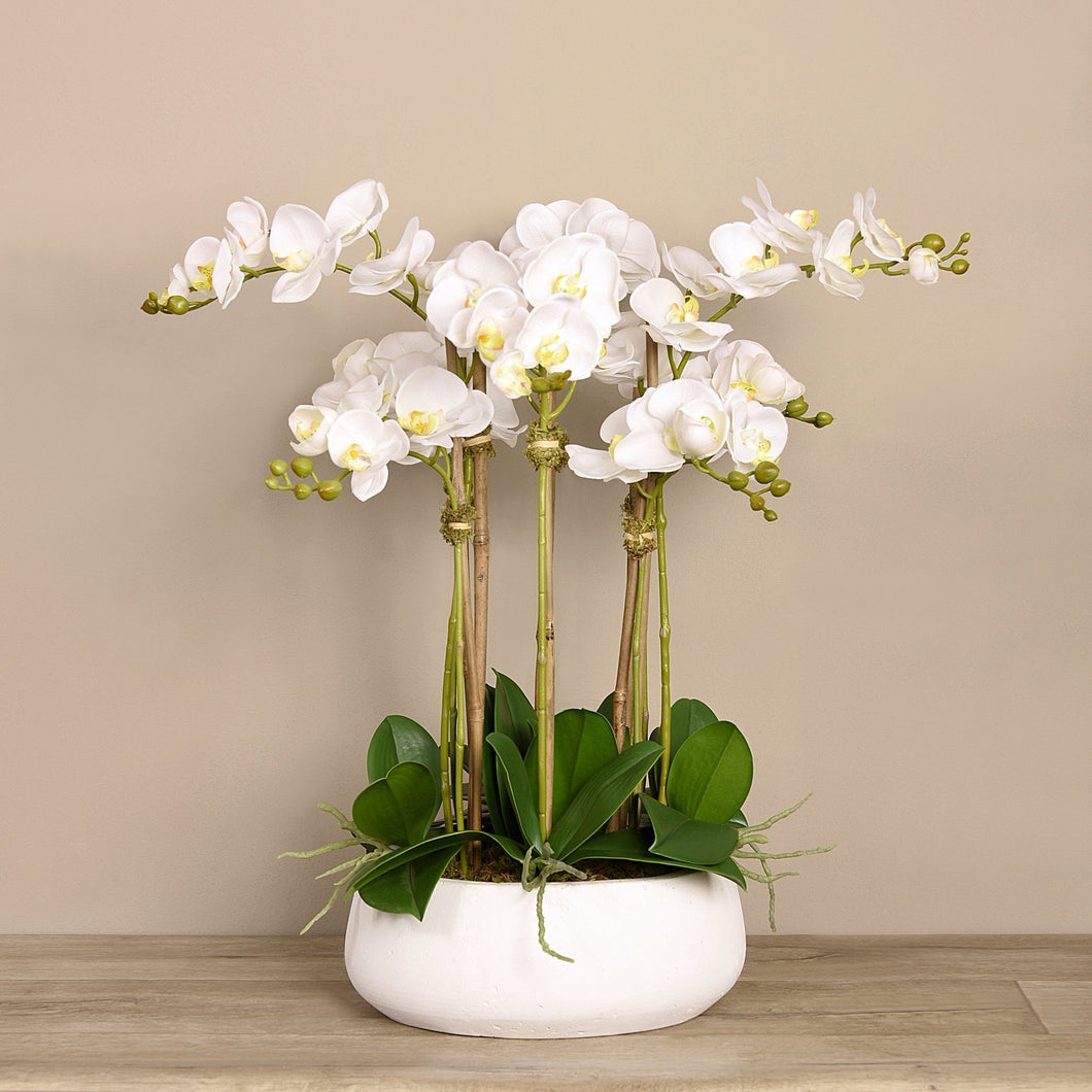 large faux floral orchid arrangement in white vase